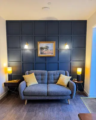 a blue couch in a living room with two lamps at The Library Cottage at The Old Library in Aberystwyth