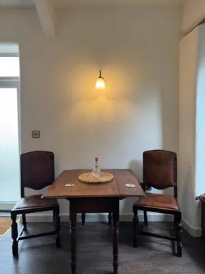 a dining room table with two chairs and a lamp at The Library Cottage at The Old Library in Aberystwyth