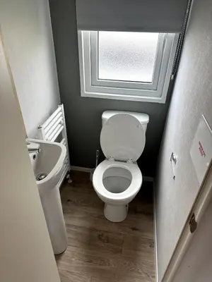 a small bathroom with a toilet and a sink at Luxury static caravan on SunnySands with mountain views in Barmouth