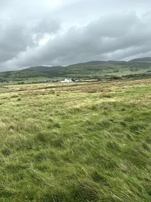 a field of grass with a house in the distance at Luxury static caravan on SunnySands with mountain views in Barmouth