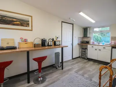 a kitchen with a counter and red stools at Sharon's Shepherd Hut in Oswestry
