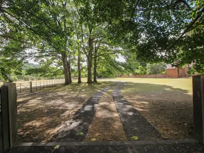 a gate to a field with trees and a fence at The Coach House in Church Stretton