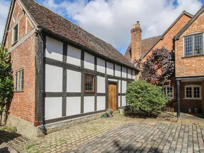 an old house with a white and black building at Courtyard Cottage in Church Stretton