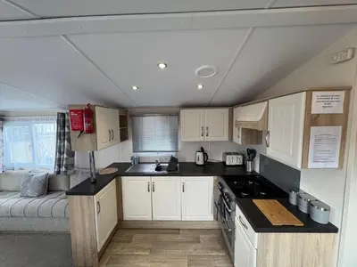 a kitchen with white cabinets and a couch in a room at T&J Seaview at Pengarreg in Llanrhystyd