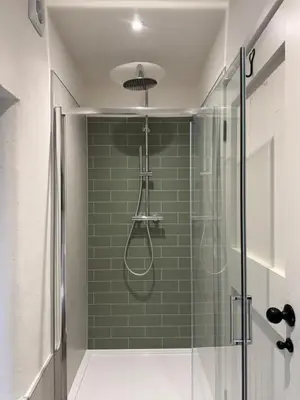a bathroom with a shower with green tile at Fishermans Cottage at The Old Library in Aberystwyth