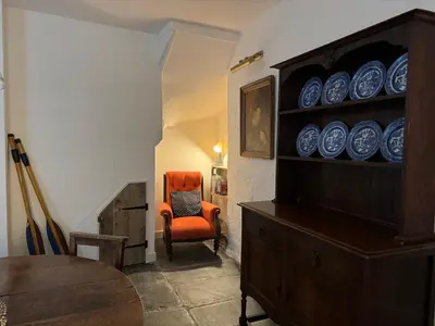 a dining room with an orange chair and blue plates at Fishermans Cottage at The Old Library in Aberystwyth