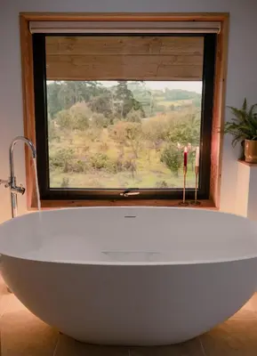 a large white bath tub in a bathroom with a window at Amberwood Lodge in Hay-on-Wye