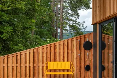 a yellow bench sitting next to a fence at Cedar Lodge in Hay-on-Wye