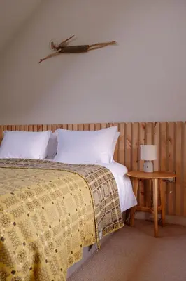 a bedroom with a bed and a table with a lamp at Cedar Lodge in Hay-on-Wye