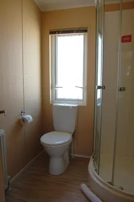 a bathroom with a toilet and a window and a shower at Morannedd Lodge Barmouth Bay in Llanddwywe