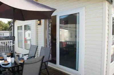 a patio with an umbrella and a table and chairs at Morannedd Lodge Barmouth Bay in Llanddwywe