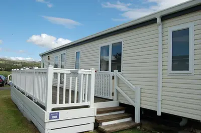 a mobile home with a white porch and stairs at Morannedd Lodge Barmouth Bay in Llanddwywe