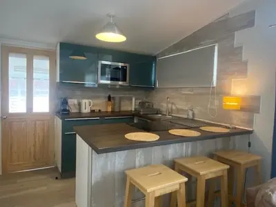 a kitchen with blue cabinets and wooden stools at Chalet 8 Erw Porthor Happy valley in Tywyn