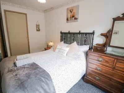a bedroom with a bed with a dresser and a mirror at Old Post Office in Maentwrog
