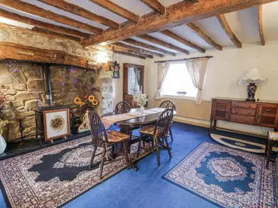 a dining room with a table and chairs and a stone wall at Old Post Office in Maentwrog