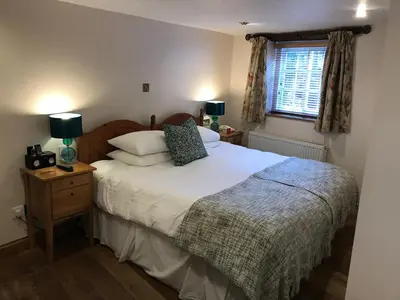 a bedroom with a bed with white sheets and a window at Sebastians in Oswestry