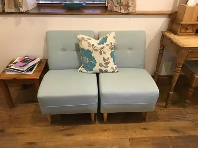 a blue chair with two pillows on it next to a table at Sebastians in Oswestry