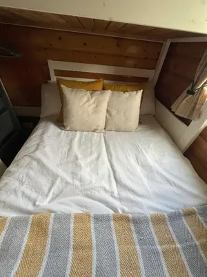 a bed with white sheets and pillows in a room at Log Cabin Retreat Snowdonia in Trawsfynydd