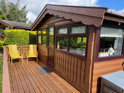 a large wooden deck with two chairs on it at Log Cabin Retreat Snowdonia in Trawsfynydd
