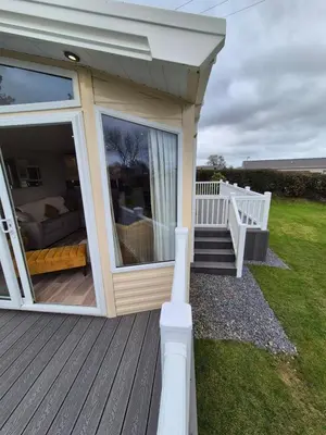 a house with a large sliding glass door on a deck at Harries Superior Lodge Ocean in New Quay