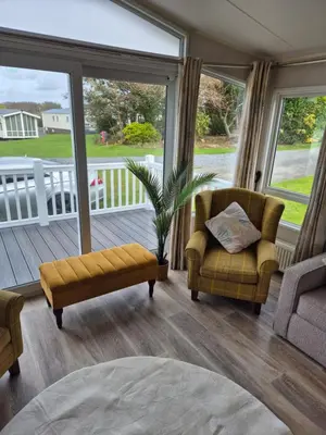 a living room with a couch and chairs on a porch at Harries Superior Lodge Ocean in New Quay