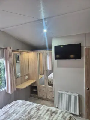 a bedroom with a bed and a tv on the wall at Harries Superior Lodge Ocean in New Quay