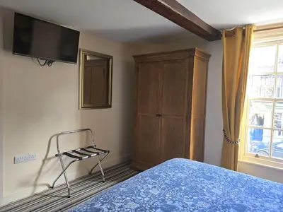 a bedroom with a bed and a chair and a cabinet at Family Room - The Unicorn Hotel in Llanidloes