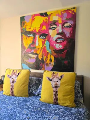 two giraffe pillows on a bed with a painting at Family Room - The Unicorn Hotel in Llanidloes