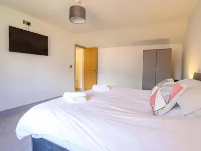 a bedroom with a large white bed with a flat screen tv at Preesgweene Farmhouse in Oswestry