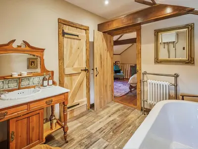 a bathroom with a tub and a sink and a mirror at Rustic Retreat in Llangadog