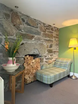 a living room with a chair and a stone wall at Y Meirionnydd Boutique Hotel in Dolgellau