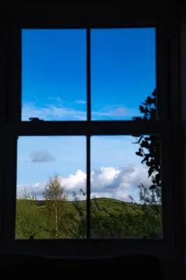 a window with a view of a field seen through it at Little Cott - Cosy Welsh Cottage, a hiking retreat in Maentwrog