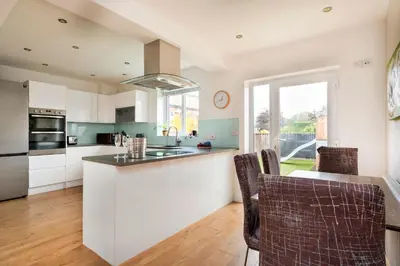a kitchen with white cabinets and a table with chairs at Finest Retreats - Elizabeth House in Kington