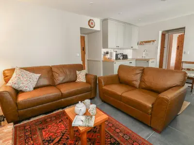 a living room with two brown leather couches and a table at Llainorfa in New Quay