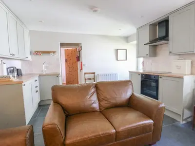 a living room with a brown couch in a kitchen at Llainorfa in New Quay