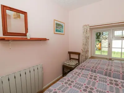 a bedroom with a bed and a mirror and a window at Llainorfa in New Quay