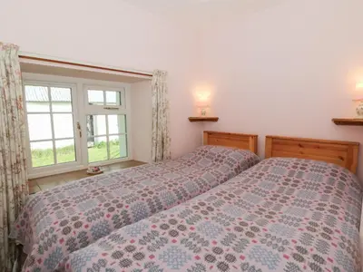 a bedroom with two beds and a window at Llainorfa in New Quay