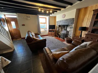 a living room with leather couches and a fireplace at Arddwyn - Cosy Welsh cottage in Penrhyndeudreath