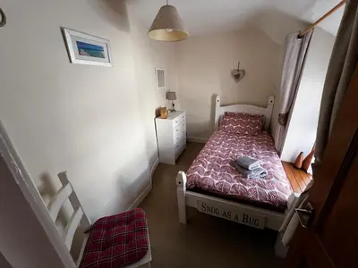 a small bedroom with a bed and a staircase at Arddwyn - Cosy Welsh cottage in Penrhyndeudreath