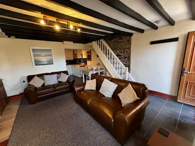 a living room with two leather couches and a staircase at Arddwyn - Cosy Welsh cottage in Penrhyndeudreath