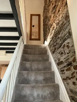 a staircase in a house with a stone wall at Arddwyn - Cosy Welsh cottage in Penrhyndeudreath