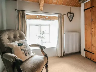 a living room with a leather chair and a window at Ty Fferm Bargoed in Aberaeron