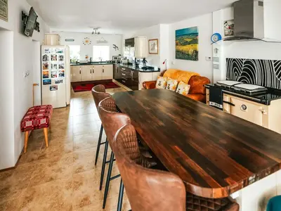 a kitchen and living room with a wooden table and chairs at Ty Fferm Bargoed in Aberaeron