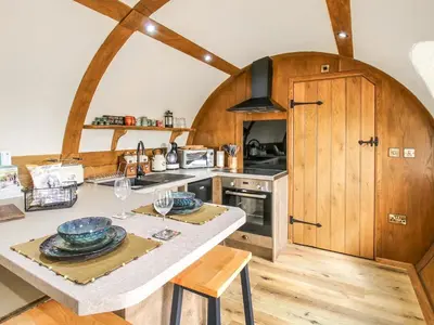 a kitchen with wooden cabinets and a table with plates at Shires End in Leominster