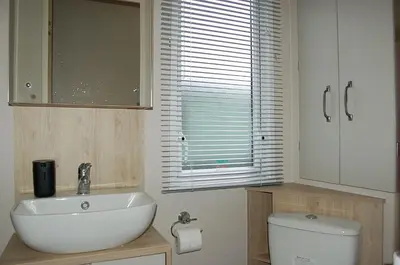 a bathroom with a sink and a toilet and a window at Premier Caravan 10 at The Vaenol, Tywyn in Tywyn