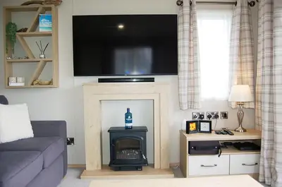 a living room with a fireplace with a tv above it at Premier Caravan 10 at The Vaenol, Tywyn in Tywyn