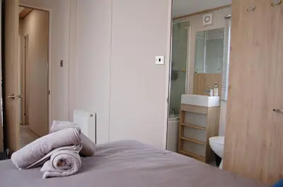 a bedroom with a bed and a bathroom with a sink at Premier Caravan 10 at The Vaenol, Tywyn in Tywyn