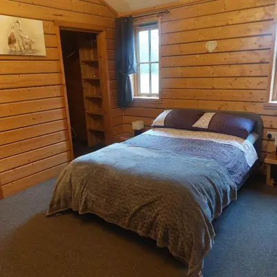 a bedroom with a bed in a log cabin at Alpaca cabin-mountain view-hot tub-rural retreat in Llanbrynmair