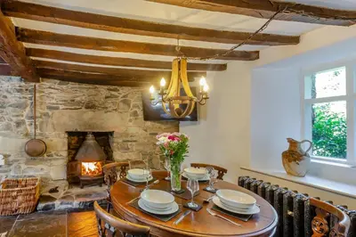 a dining room with a table and a fireplace at 2 Bed in Islawrdref oc-w33317 in Penmaenpool