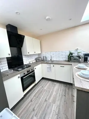 a kitchen with white cabinets and a wooden floor at Modern 1 Bed Apartment Sleeps 2 in Llanbadarn-fawr